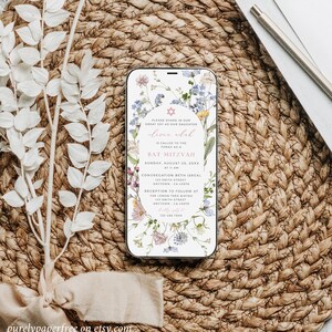 May include: A floral phone screen mockup with a Bat Mitzvah invitation for Olivia Adal. The invitation includes the date, time, and location of the event. The invitation is decorated with a floral design and a Star of David.