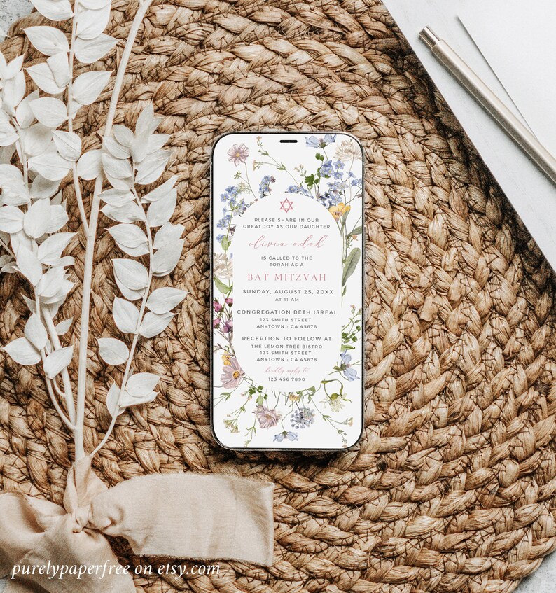 May include: A floral phone screen mockup with a Bat Mitzvah invitation for Olivia Adal. The invitation includes the date, time, and location of the event. The invitation is decorated with a floral design and a Star of David.