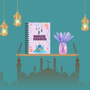 以下が含まれることがあります： 「RAMAZAN PLAN/WISH」の文字とモスクのイラストが描かれたラマダン用プランナーノート。ノートは、ラベンダーの花瓶と吊り下げられたランタンのある木製の棚に置かれています。背景は、モスクのシルエットが描かれたティール色です。