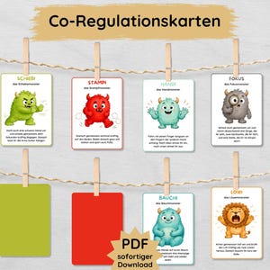 May include: A set of six rectangular cards titled Co-Regulationskarten, featuring colorful cartoon monsters like a green Schiebi, red Stampi, blue Handi, gray Fokus, and orange Lowi. Each card includes German text and is clipped to a string with wooden pins.