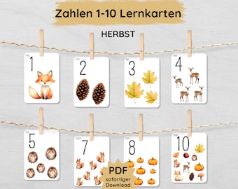 May include: Ten printable flashcards featuring autumn-themed illustrations and numbers 1 through 10. The cards are white with black numbers and images of a fox, pine cones, maple leaves, deer, hedgehogs, squirrels, pumpkins, and acorns.