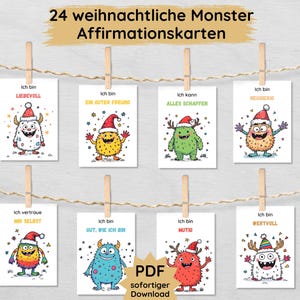 Könnte beinhalten: Acht Affirmationskarten mit Cartoon-Monstern, die Weihnachtsmützen tragen. Jede Karte zeigt ein andersfarbiges Monster und eine positive Affirmation auf Deutsch. Die Karten hängen mit Wäscheklammern an einer Schnur.