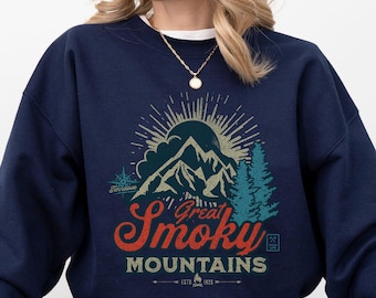 Könnte beinhalten: Ein marineblauer Pullover mit einem Vintage-Grafikdruck von Bergen und Bäumen. Der Text auf dem Pullover lautet "Great Smoky Mountains".