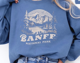 May include: A blue sweatshirt with a white graphic of a mountain landscape and the text "Banff National Park".