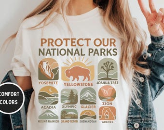 May include: White t-shirt with the text "Protect Our National Parks" and illustrations of different national parks, including Yosemite, Yellowstone, Joshua Tree, Acadia, Olympic, Glacier, Zion, Mount Rainier, Grand Teton, Shenandoah, and Arches.