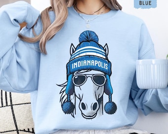 Könnte beinhalten: Ein hellblaues Sweatshirt mit einem weißen Pferd, das einen blau-weißen Hut mit der Aufschrift "Indianapolis" trägt. Das Pferd trägt eine Sonnenbrille.