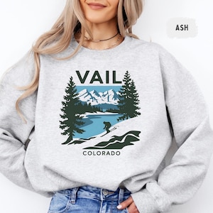 May include: Gray sweatshirt with a graphic print of a skier in the mountains with the text "Vail Colorado".