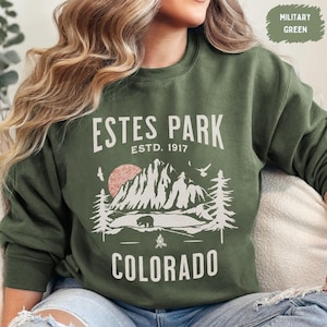 May include: A green sweatshirt with a white graphic design featuring a mountain range, a bear, and the text "ESTES PARK ESTD. 1917 COLORADO".