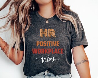 May include: A dark gray heather t-shirt with the text "HR Positive Workplace Vibes" in orange, yellow, and red lettering.
