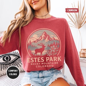 May include: Crimson-colored sweatshirt with a circular graphic featuring a mountain range, a deer, and the text "Estes Park Rocky Mountains Colorado." The sweatshirt also has the words "Comfort Colors" on it.