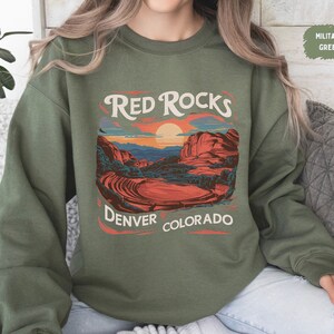 May include: A green sweatshirt with a graphic print of a sunset over red rocks with the text "Red Rocks Denver Colorado".