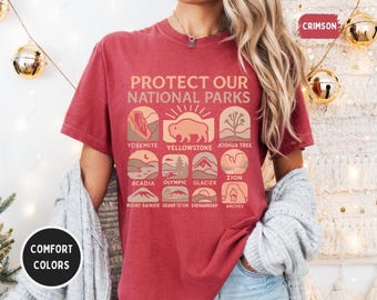 May include: Red t-shirt with the text "Protect Our National Parks" and illustrations of different national parks, including Yosemite, Yellowstone, Joshua Tree, Acadia, Olympic, Glacier, Zion, Mount Rainier, Grand Teton, Shenandoah, and Arches.