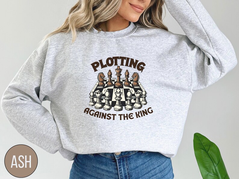 May include: A gray sweatshirt with the text "Plotting Against The King" and a graphic of a chessboard with chess pieces.