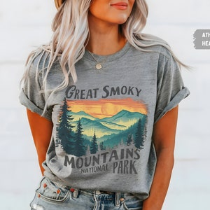 May include: A grey t-shirt with a graphic print of a sunset over mountains with the text "Great Smoky Mountains National Park".