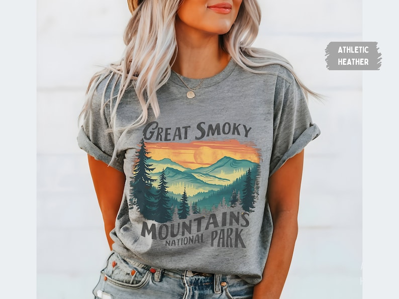 May include: A grey t-shirt with a graphic print of a sunset over mountains with the text "Great Smoky Mountains National Park".