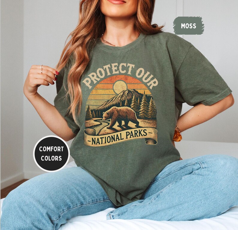 May include: A green t-shirt with a vintage-style graphic of a bear walking through a forest with the text "Protect Our National Parks".