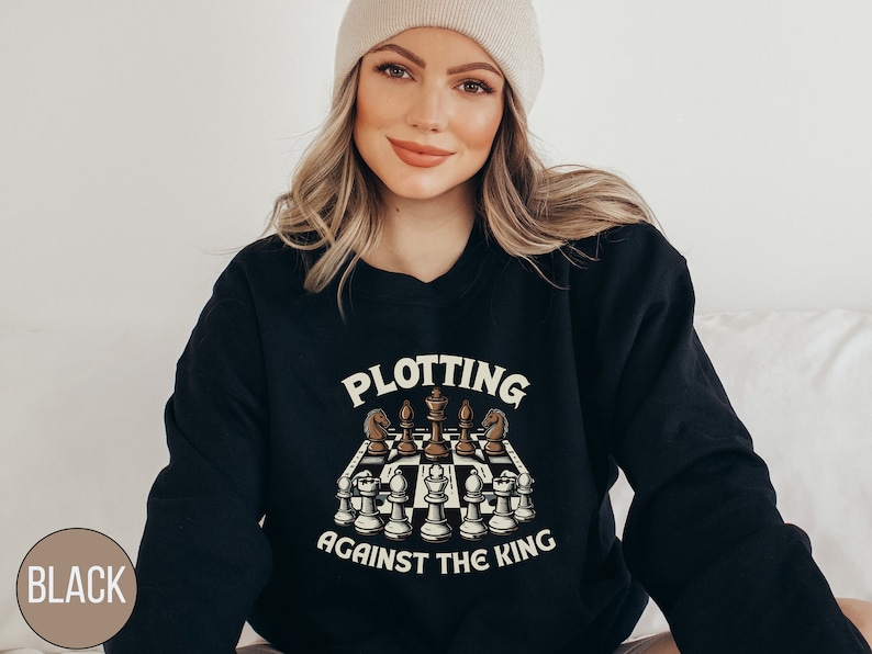 May include: Black sweatshirt with a chessboard graphic and the text "Plotting Against The King".