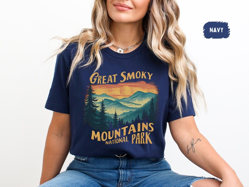May include: A navy blue t-shirt with a vintage-style graphic of a mountain range and sunset. The text "Great Smoky Mountains National Park" is printed on the shirt.