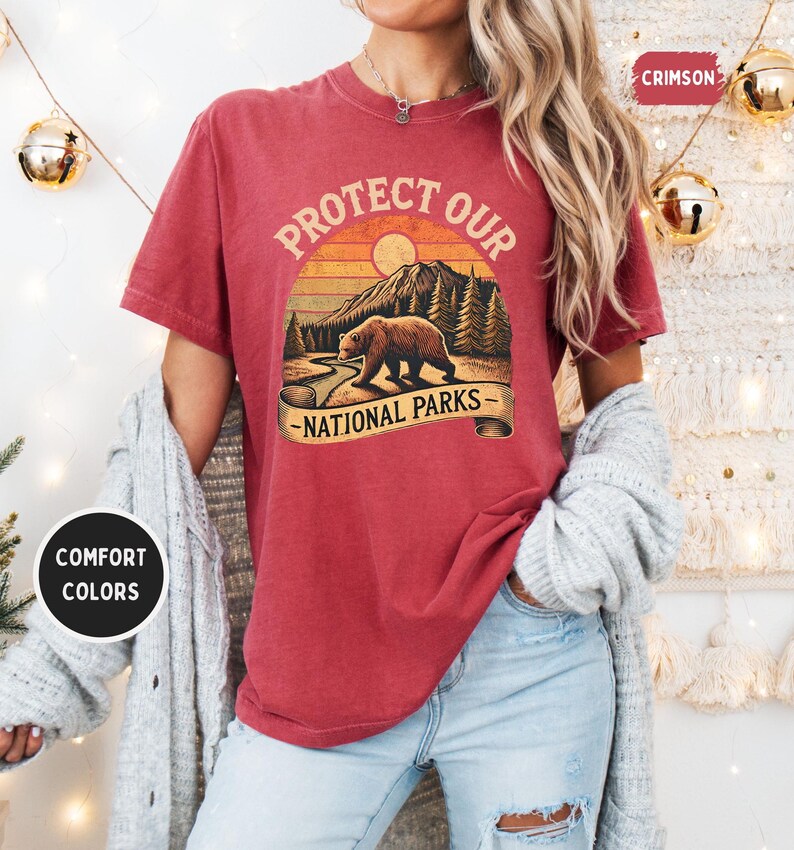 May include: A red t-shirt with a vintage-style graphic of a bear in a forest with the text "Protect Our National Parks".