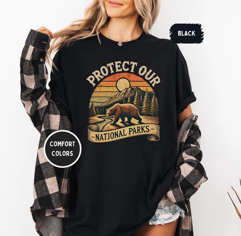 May include: Black t-shirt with a vintage-style graphic of a bear in front of a mountain and sunset. The text "Protect Our National Parks" is printed on the shirt.
