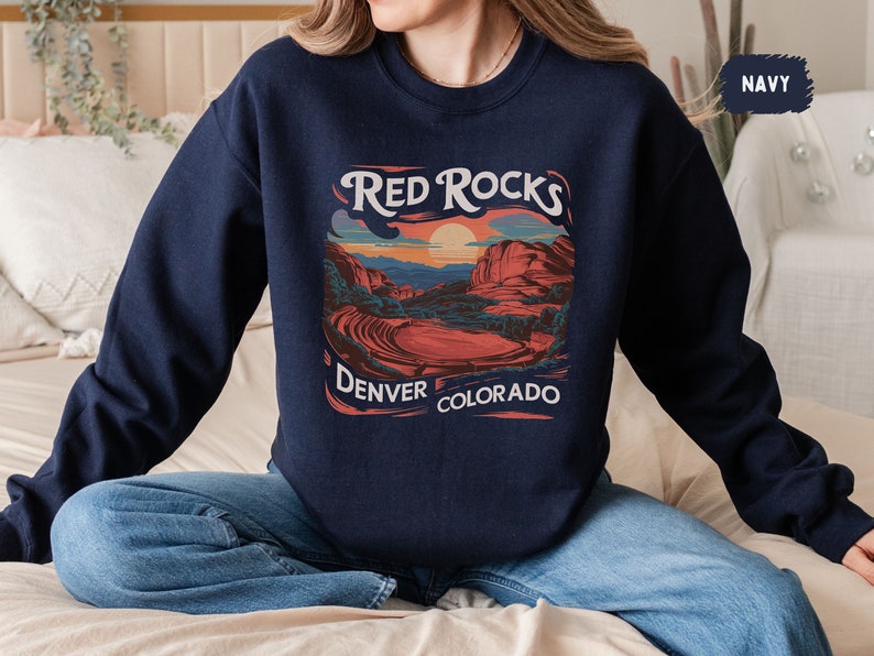 May include: A navy blue sweatshirt with a graphic print of a sunset over red rocks. The text "Red Rocks Denver Colorado" is printed below the graphic.