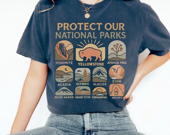 May include: A navy blue t-shirt with the text "Protect Our National Parks" and illustrations of different national parks, including Yellowstone, Yosemite, Joshua Tree, Acadia, Olympic, Glacier, Zion, Mount Rainier, Grand Teton, Shenandoah, and Arches.