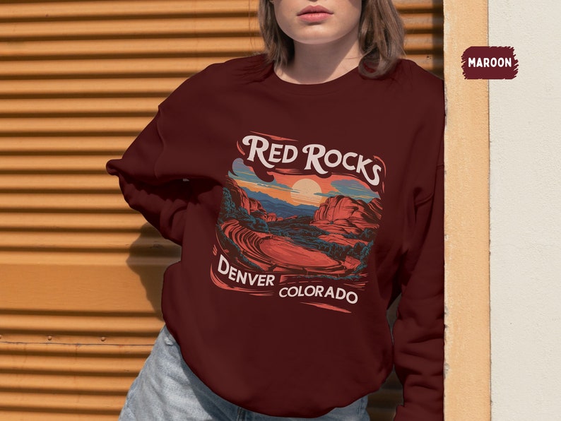 May include: A maroon sweatshirt with a graphic print of a red rock landscape. The text "Red Rocks Denver Colorado" is printed on the sweatshirt.