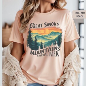 May include: A heather peach t-shirt with a vintage-style graphic of a mountain range with a sunset and the text "Great Smoky Mountains National Park".