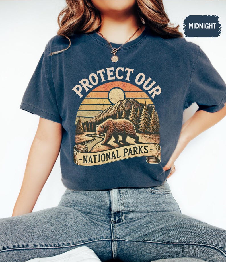 May include: A navy blue t-shirt with a vintage-style graphic of a bear walking through a forest with the text "Protect Our National Parks".