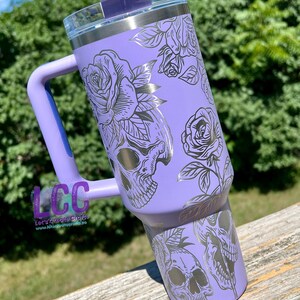 May include: A purple stainless steel tumbler with a black and silver skull and rose design. The tumbler has a handle and a lid. The text "Let's Create Crafts" and "www.letscreatecrafts.co" is on the handle.
