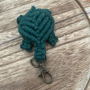 May include: A dark green crocheted turtle keychain with a metal clasp.