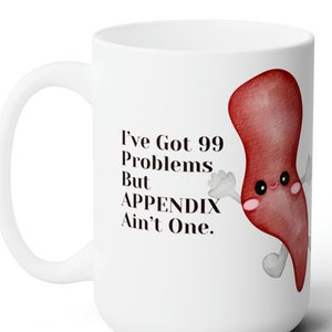 May include: White ceramic mug with a red cartoon appendix with a smiling face and the text "I've Got 99 Problems But APPENDIX Ain't One."