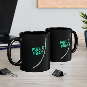 May include: Two black coffee mugs with a green and white medical tubing graphic and the text "Pull & Pray".