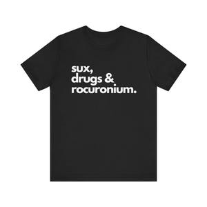 Może przedstawiać: Czarny T-shirt z białym tekstem, który brzmi "sux, drugs & rocuronium."