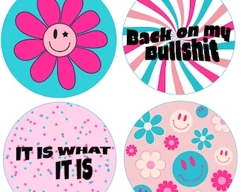 Puede incluir: Cuatro pegatinas redondas con diferentes diseños. La primera pegatina tiene una flor rosa con una cara sonriente sobre un fondo azul. La segunda pegatina tiene un diseño de remolino rosa y azul con el texto "Back on my Bullshit". La tercera pegatina tiene un fondo rosa con estrellas azules y el texto "It is what it is". La cuarta pegatina tiene un fondo rosa con flores azules y blancas y caras sonrientes.