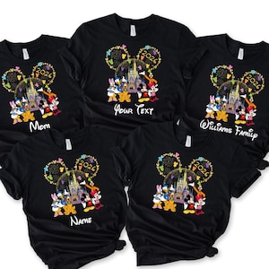 Puede incluir: Camisetas negras con un gr&aacute;fico colorido de personajes de Disney, un castillo y el a&ntilde;o 2026. Las camisetas tienen texto que dice "Mom", "Your Text", "Williams Family" y "Name".