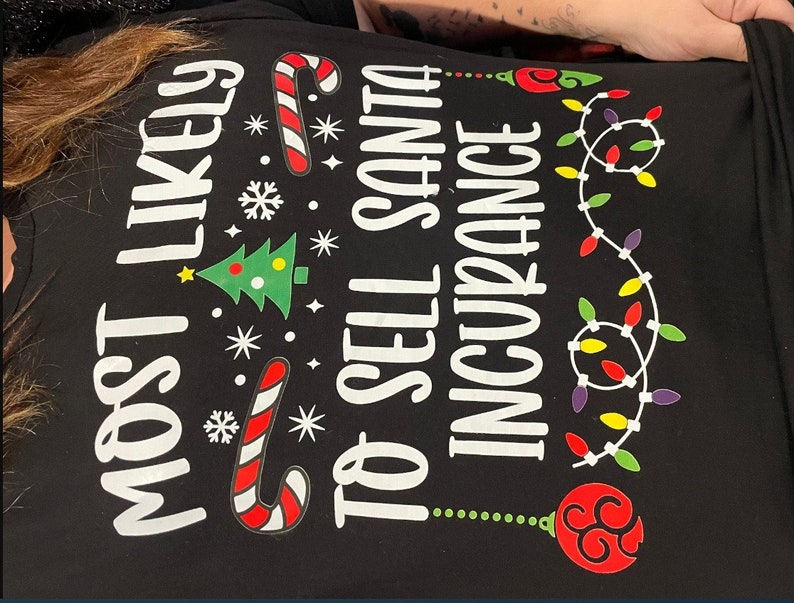 May include: Black t-shirt with white text that reads "Most Likely to Sell Santa Insurance". The text is surrounded by Christmas-themed graphics, including a candy cane, a Christmas tree, snowflakes, and a string of lights.