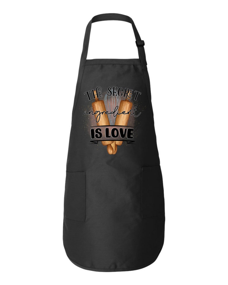 May include: Black apron with a pocket and the text "The Secret Ingredient Is Love" with a graphic of a whisk and rolling pins.