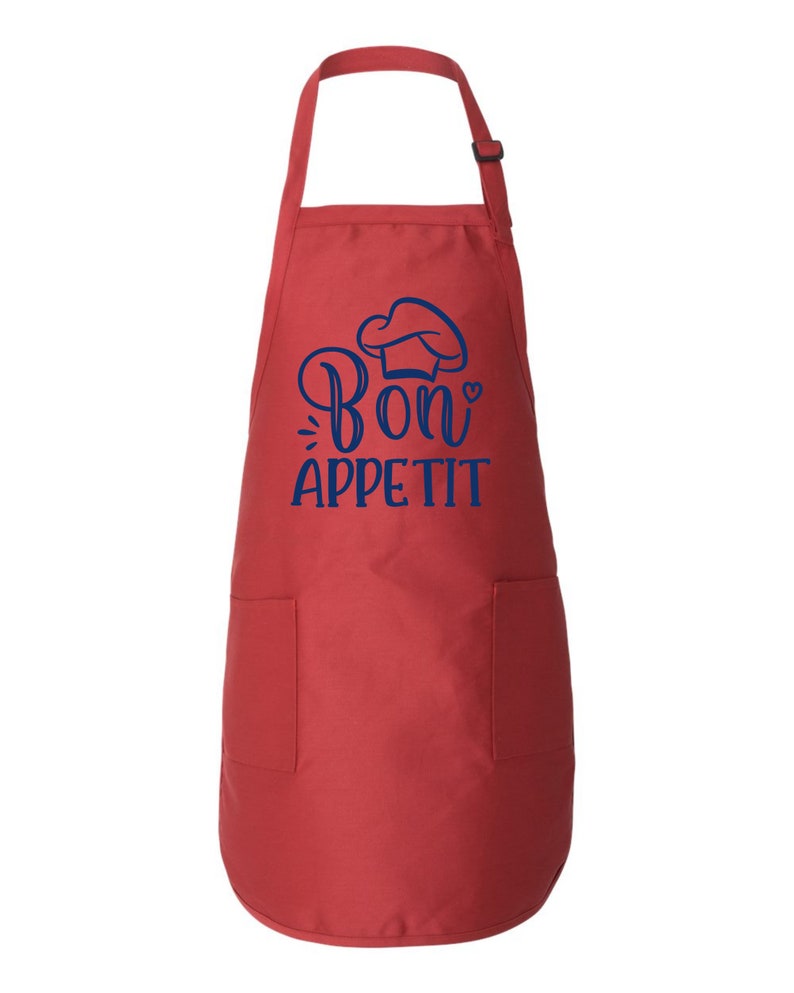 Peut inclure: Tablier de cuisine rouge avec un chapeau de chef bleu et le texte "Bon app&eacute;tit" avec un petit c&oelig;ur.