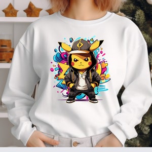 May include: White sweatshirt with a graphic print of a yellow Pikachu wearing a black and white hoodie, a black baseball cap with a white letter P, and black pants. The Pikachu is standing on a colorful background with abstract shapes.
