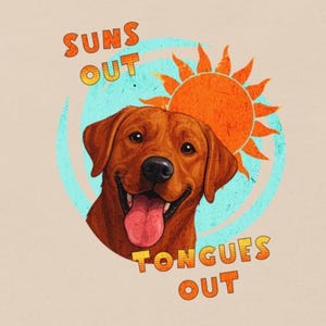 Puede incluir: Camiseta beige claro con un diseño de un Labrador marrón sonriendo con la lengua fuera. El diseño incluye un sol naranja y el texto "Suns Out Tongues Out" en naranja y amarillo.