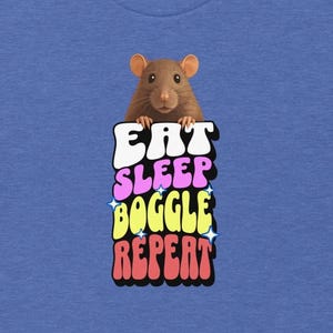 Op de afbeelding: Blauw T-shirt met een bruine rat boven de tekst "EAT SLEEP BOGGLE REPEAT" in een kleurrijk, retro lettertype. Het ontwerp heeft een speelse, cartoonachtige stijl, perfect voor casual wear.