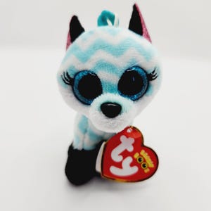 May include: A blue and white striped plush toy with large blue eyes and a black nose. The toy is holding a red heart-shaped tag with the word "Ty" on it.