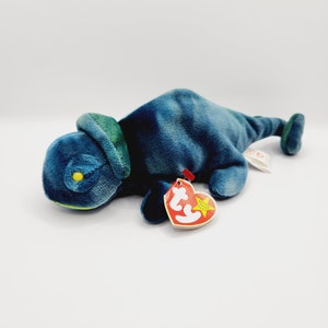 May include: A blue and green tie-dye beanie baby chameleon plush toy with a red and yellow tag that reads "Beanie Babies" and has a star on it.