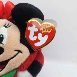 Puede incluir: Juguete de peluche rojo y negro de un rat&oacute;n de dibujos animados que lleva un vestido rojo y un lazo verde. El juguete tiene una etiqueta Ty Beanie Ballz.