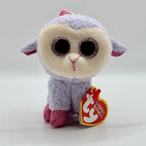 May include: Purple and white plush lamb with sparkly eyes. The lamb is a keychain with a Ty tag that says "Basket Beanies".