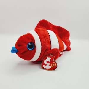 May include: Red and white striped plush clownfish with a blue mouth and a Ty Beanie Baby tag.