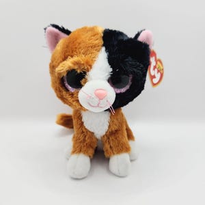 May include: A set of three ceramic mugs with a speckled, matte finish. The mugs are in shades of cream, light gray, and dark gray. Each mug has a simple, minimalist design and a rounded handle.