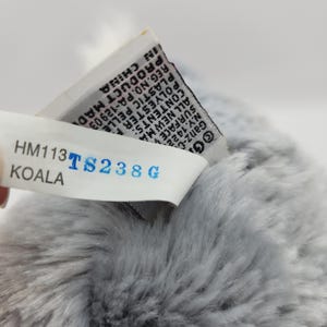 May include: Gray plush koala stuffed animal with a white tag that reads "HM113 TS238G KOALA" and a smaller tag with text in black and white.