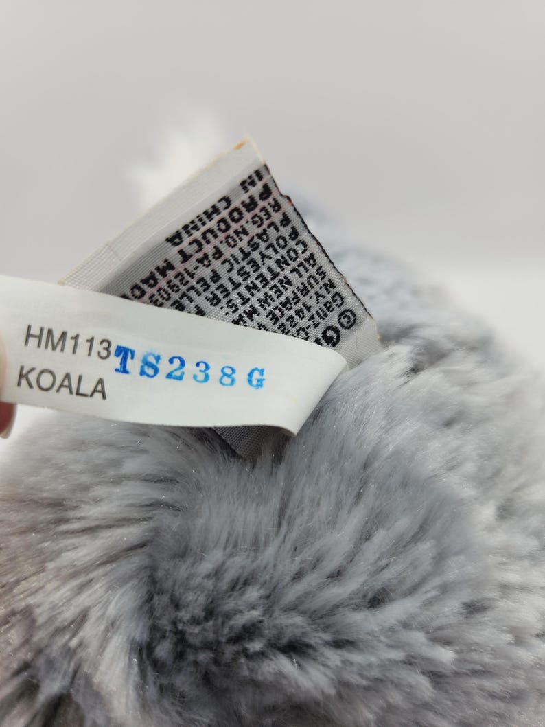 May include: Gray plush koala stuffed animal with a white tag that reads "HM113 TS238G KOALA" and a smaller tag with text in black and white.